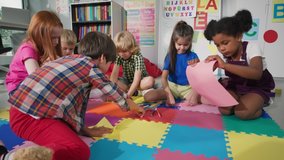 group of preschool children draw in classroom sitting on floor. Multi-ethnic boys and girls study and play painting on paper at elementary school. Kids drawing and painting at school concept.  - Powered by Shutterstock - Get 15% off with code: PIKWIZARD15
