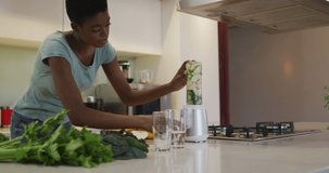 Animation of home grown text and leaves over happy african american woman cooking. ecology, cooking, food concept digitally generated video.