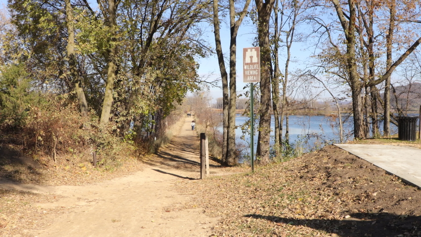 Bright autumn day in Wisconsin wetlands.  Gravel path to enjoy the wetlands. Blue sky with a few clouds. Shadows from the sun through the trees. Light breeze in the air. Signage marking viewing area