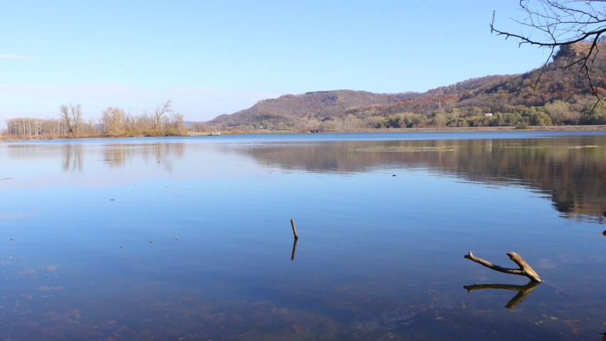water filled wetland in western Wisconsin on a bright clear autumn day. Tree branches sticking out of the water. Bluffs seen in the background. Reflection off the calm water. 