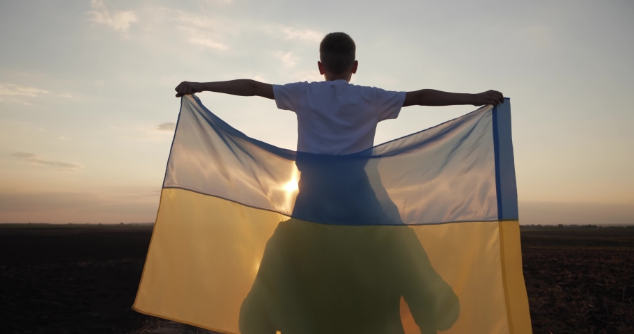 A Ukrainian soldier carries a child in his arms holding the flag of Ukraine Royalty-Free Stock Footage #1093700403