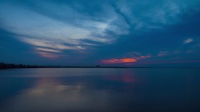 View of magical brilliant bewitching reflection in calm blue quiet Black Sea, against background of sea horizon with cloudy multi-colored sky and bright evening sunset. 4K UHD timelapse video