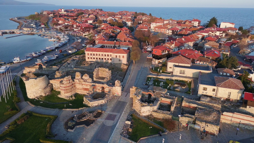 Bird's eye view of the ancient sea town of Nesebar with green spring parks and narrow streets lined with old houses with people walking on a peninsula in the Black Sea, Bulgaria. UHD 4K video