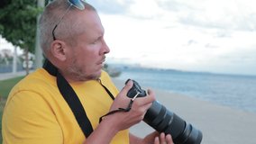 A man takes a picture on a camera with a large lens. Outdoors in the city on a sunny summer day.