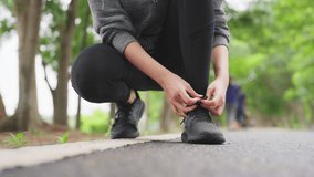 Closeup of woman tying shoe laces. Asian female sport fitness runner getting ready for jogging outdoors in public park - Powered by Shutterstock - Get 15% off with code: PIKWIZARD15