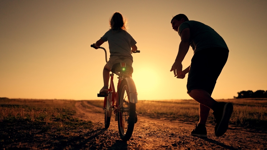 Happy family. Father teaches daughter to ride bike in park. father helps his daughter in her studies. happy child dreams of traveling by bike. child is learning to ride bike. Royalty-Free Stock Footage #1093715941