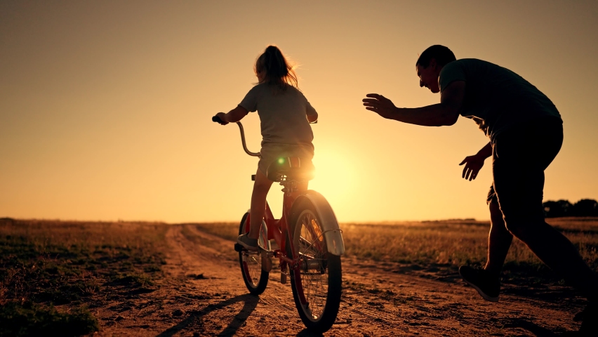 Happy family. Father teaches daughter to ride bike in park. father helps his daughter in her studies. happy child dreams of traveling by bike. child is learning to ride bike. | Shutterstock HD Video #1093715941