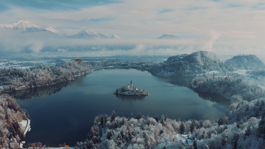 Amazing Lake Bled, Slovenia on a beautiful golden morning in wintertime. Snowy mountains in the background. Peaceful nature, fresh air, clean blue water. Top travel destination. Eco travel. Royalty-Free Stock Footage #1093718923