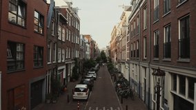 Narrow street in a residential area of Amsterdam. Bicycles and cars are parked near residential buildings. Drone video of the streets of the historic city center. Amsterdam, Netherlands