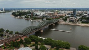 A large empty ferry floats under a bridge located in the historic center of Cologne. Wide river Rhine from a bird's eye view. Beautiful places in Germany, drone video.