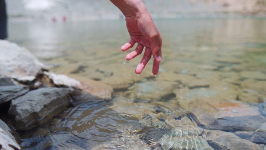 Human hand gently touching water in the calm Himalayan Lake Deepak Tal, Himachal Pradesh. Traveler enjoying feel the nature. Slow motion shot of water drops falling from wet fingers. | Shutterstock HD Video #1093722033