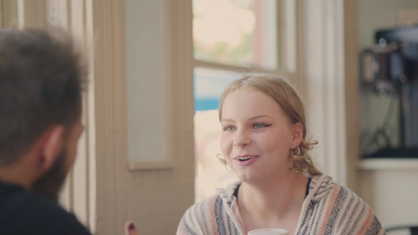 Girl talking in positive conversation with a guy in a bright cafe. Slow motion.