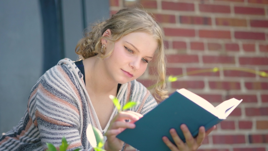 Close up of girl student reading a book outside of a school building. Slow motion. Royalty-Free Stock Footage #1093723201