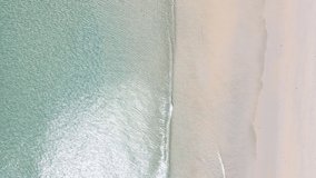Professional video 4k ProRes 4:2:2 Top-down ocean wave Aerial video beautiful closeup shot beach and seawater on wave on sand in sunset time (Top-view) nature and travel concept video.
