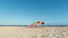 4k slow motion video of a girl doing morning yoga routine  at the beach of Baltic sea over clear cloudless blue sky