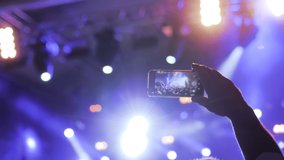 Man hands silhouette taking photo or recording video of live music concert with smartphone in front of stage of nightclub - close up. Photography, entertainment, technology concept