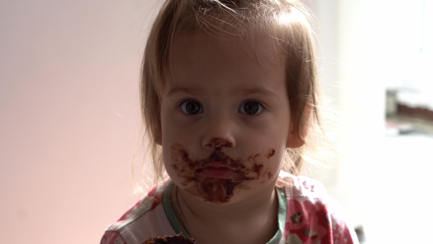Close up baby dirty Face. Funny child eat chocolate. little toddler kid in the kitchen eating candy in the morning. happy family eats sweets girl dream concept. lifestyle cocoa confection.Childhood Royalty-Free Stock Footage #1093732487