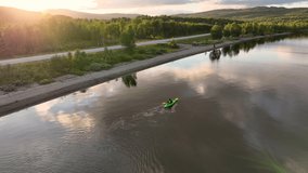 Aerial drone video above girl paddling in green kayak, sunset, mountain lake in Scandinavian mountains. Slow motion, Norway, Sweden