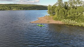 Slow motion panning video on women in green kayak stopped beside small island, lake in Scandinavian mountains. Sweden, Norway 