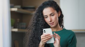 Attractive brunette woman girl with curly hair hispanic housewife look at gadget display chatting on mobile phone use smartphone for distant communication read sms from boyfriend play internet game - Powered by Shutterstock - Get 15% off with code: PIKWIZARD15