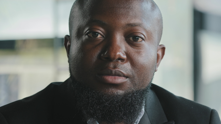 Portrait of sad african man male businessman teacher coach upset serious ethnic biracial bearded adult plus size thick guy with dark skin wears black suit sit in modern office space looking at Royalty-Free Stock Footage #1093733829