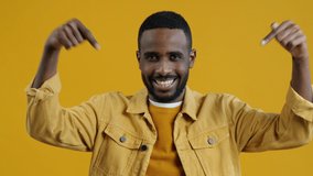 Portrait of handsome African American man pointing down and winking asking for subscribers and followers on yellow background. People and blogging concept. - Powered by Shutterstock - Get 15% off with code: PIKWIZARD15