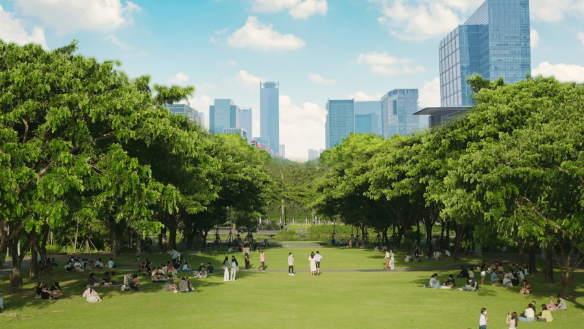 People relax on the green lawn in public green park with cityscape background Royalty-Free Stock Footage #1093739351