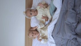 In the close-up video, the sisters are smiling. They perform a dance under the covers, moving their hands chaotically, as small children usually do. Music invigorates them. vertical video