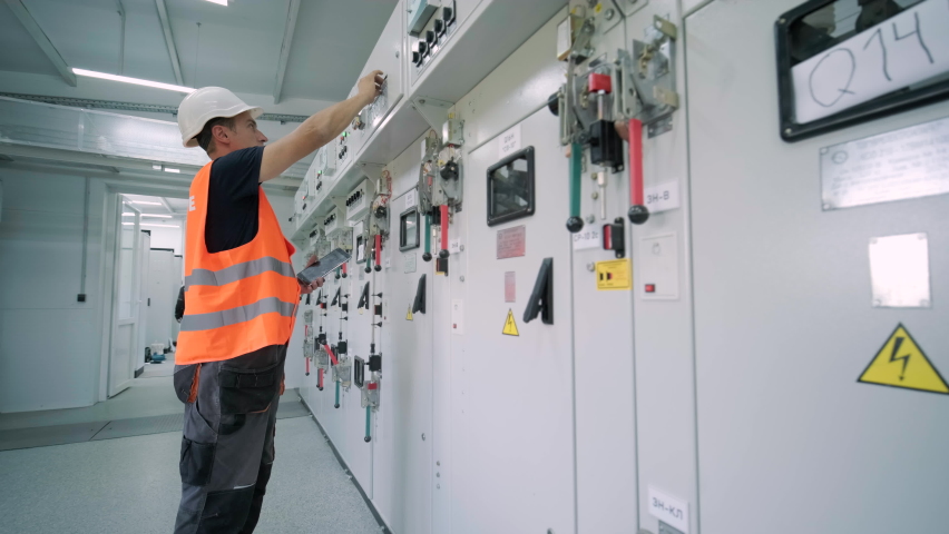 Electrical engineer working check the electric current voltage and overload at front of load center cabinet or consumer unit for maintenance in main power distribution system room. Royalty-Free Stock Footage #1093741197