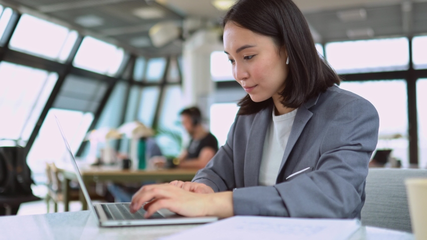 Young Asian business woman professional marketing manager using laptop. Female chinese businesswoman working on computer digital management sitting at work in big modern corporate office space. Royalty-Free Stock Footage #1093742119