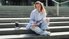 Pretty blonde girl college student writing in notebook sitting on stairs outside campus with laptop elearning university study course, learning remote virtual classes. Web education webinars concept - Powered by Shutterstock - Get 15% off with code: PIKWIZARD15