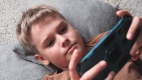 Pre teenager uses smartphone phone while lying on the floor at home.