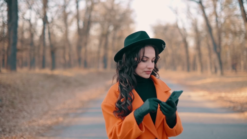 Smiling Young Beautiful Woman Uses Smartphone In autumn Park. Close Up Portrait.