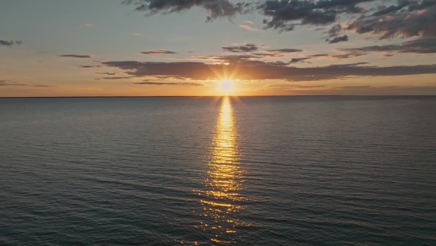 Tropical golden sunset over ocean water slow motion aerial view. Sun setting reflection on seascape. No-people sand beach at sea bay. Calm waterscape at sunny evening. Summer vacation.