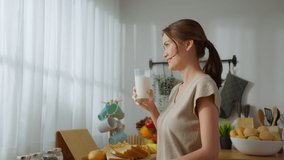 Asian young beautiful woman drinking glass of milk in kitchen at home. Attractive female looking at the window, holding and sipping a cup of milk after wake up in the morning for health care at house. - Powered by Shutterstock - Get 15% off with code: PIKWIZARD15