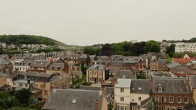Drone video, view of the historic center of the ancient city of low-rise traditional buildings, among green trees, located on a hill. Normandy, France.