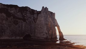 Sheer cliffs with natural arches washed by the waters of the English Channel. Etretat, France. Video from a bird's eye view, from a drone