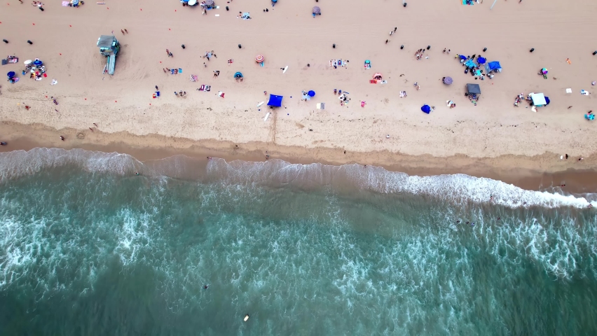 Tropical sandy Manhattan beach with ocean waves hitting coastline, aerial birds-eye