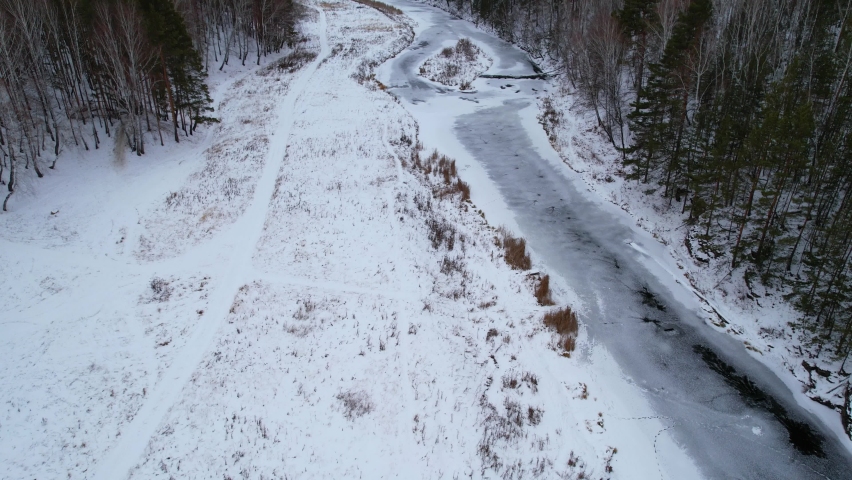 flight along the winter river and forest, aerial view of the winter landscape. snow and ice on the river