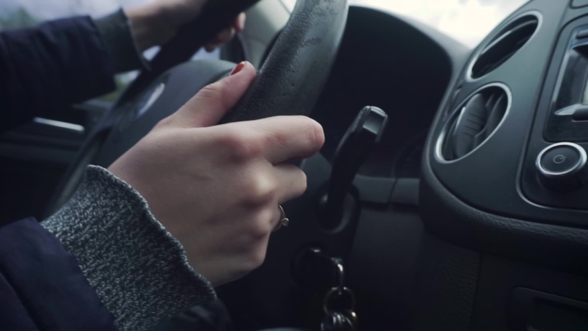 Woman's hands are turning the old steering wheel. Red manicure. Ring on the finger. Sleeves, jacket, jacket, car interior, salon. Handheld shooting. Day, overcast Royalty-Free Stock Footage #1093769795