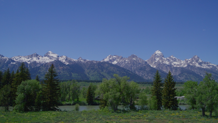 Teton Range with mountain ranges covered in snow. Beautiful sanctuary with lush green valleys, charming alpine lake and tall summits in National Park. High quality 4k footage