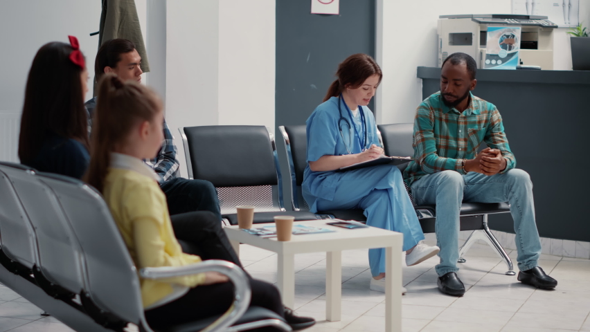 African american patient doing consultation with medical nurse taking notes in waiting room lobby. Diverse people having conversation about healthcare checkup visit and writing report. | Shutterstock HD Video #1093774395