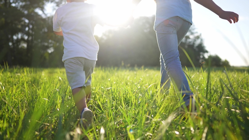happy family. brother sister runs legs close-up in the park at sunset. people in the park concept. little children joyful run. happy family summer. a group of children run in the park on the grass Royalty-Free Stock Footage #1093786663