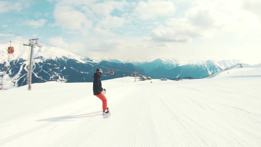 Rear view athlete snowboarder ride down slope hill on snowboard and performs maneuverable movements and tricks. Ski resort. Active lifestyle. Winter extreme sport. Nature landscape of mountain range Royalty-Free Stock Footage #1093789489