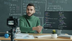 IT teacher recording lesson with digital camera explaining software coding in classroom with chalkboard. Education and vlogging concept. - Powered by Shutterstock - Get 15% off with code: PIKWIZARD15