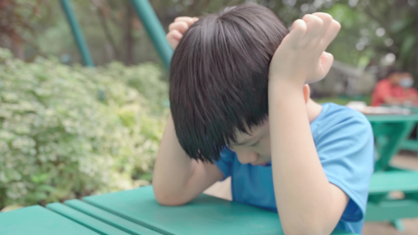 Close up of Asian autistic student child sit face down, bang and slap head with hands due to stress, anxiety and frustration. Autism stimming behavior for World Autism spectrum awareness concept | Shutterstock HD Video #1093793565