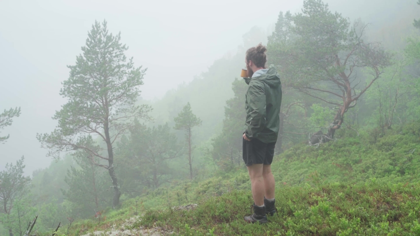 Man Drinking A Hot Coffee Or Tea Standing On A Mountainside Covered With Morning Fog. - Medium Shot