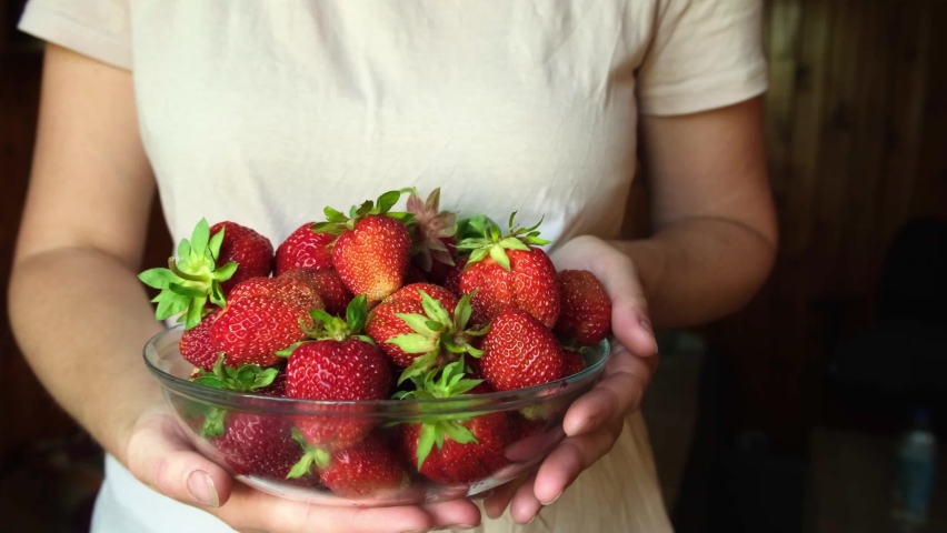 healthy eating, seasonal food. Woman hand holding bowl with ripe red fruit strawberry. Unrecognizable girl ready to eat seasonal summer red berry. Healthy organic dessert, vegan food concept