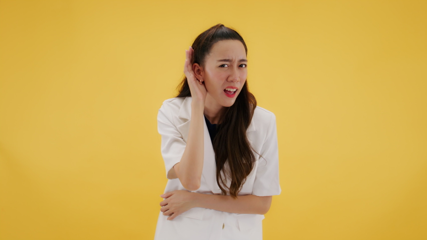 I CAN'T HEAR YOU! Attractive confident fashionable asian woman suffering from hearing with hand behind ears gesture. Young lady looking at camera with confused face. Isolated on yellow background. | Shutterstock HD Video #1093806189