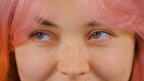Portrait of young white female with dyed pink hair looking in video camera. Cute young girl with colored hair posing for royalty free footage clip in 4K